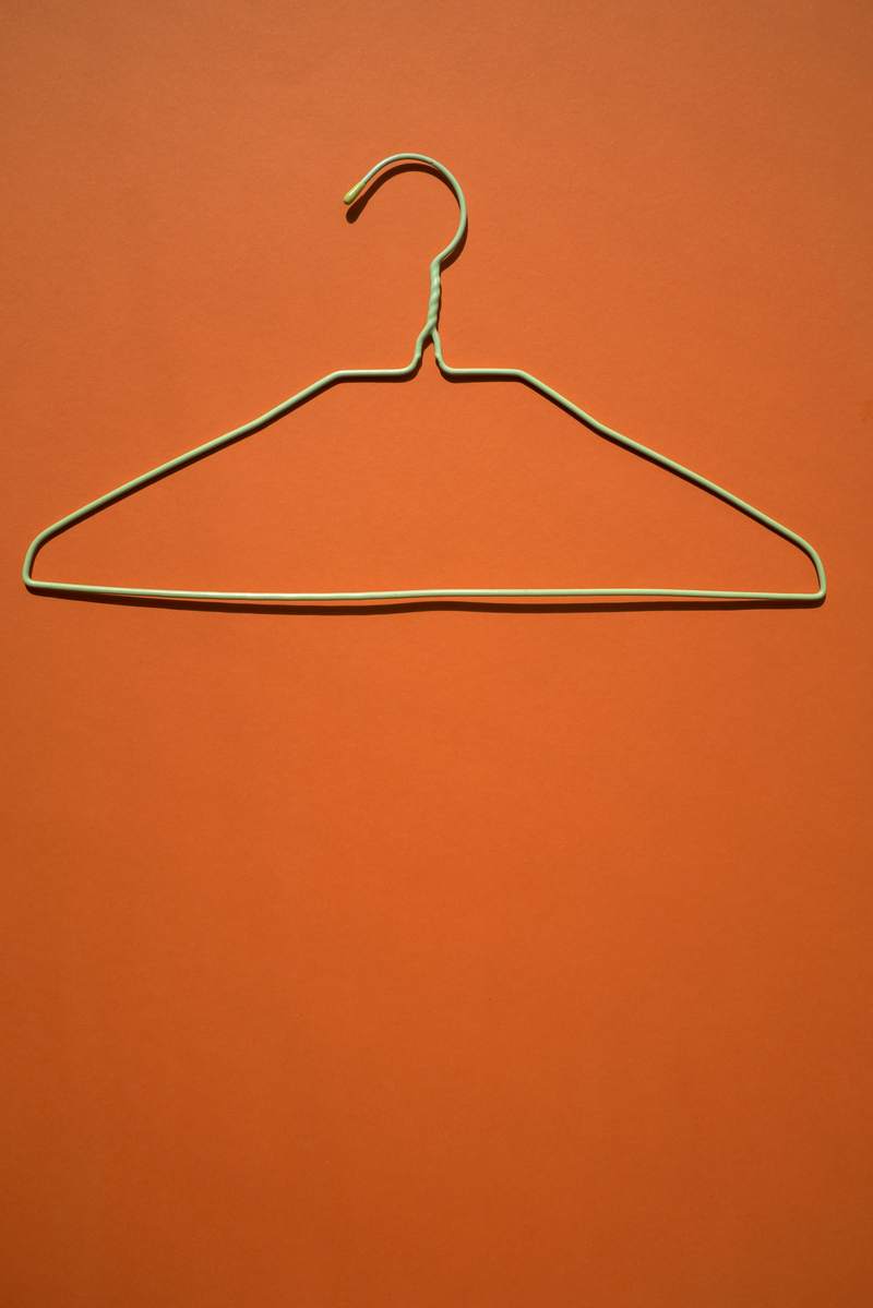 Percha de alambre sobre un muro color naranja