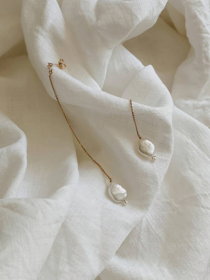 Aros de perlas sobre lino blanco.