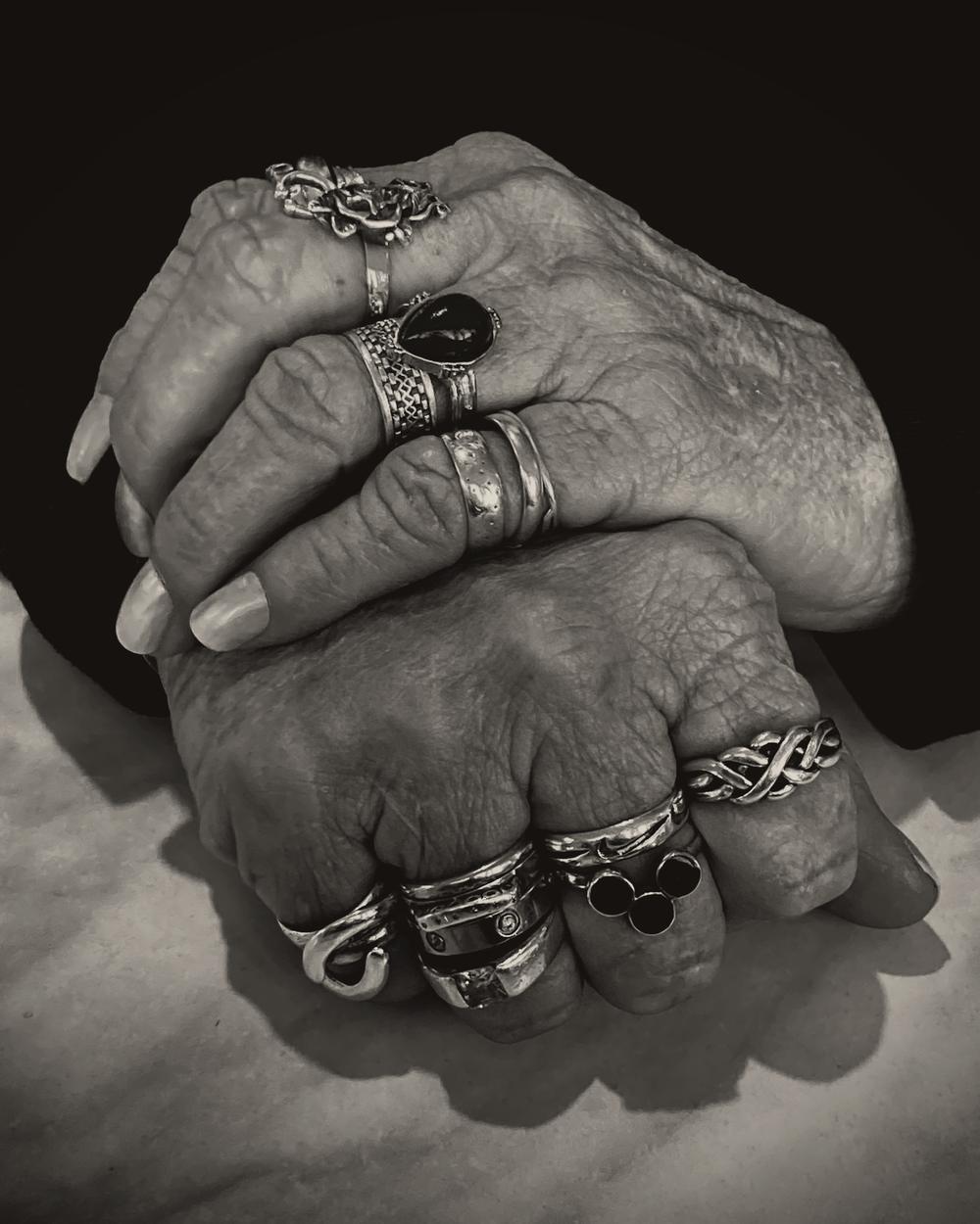 Dos manos entrelazadas con anillos de plata, en blanco y negro