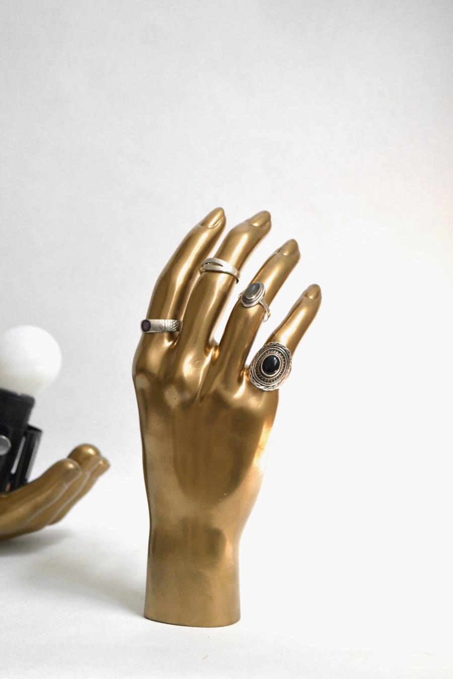 Una mano de maniquí dorada con anillos de plata, uno de ellos con una piedra negra
