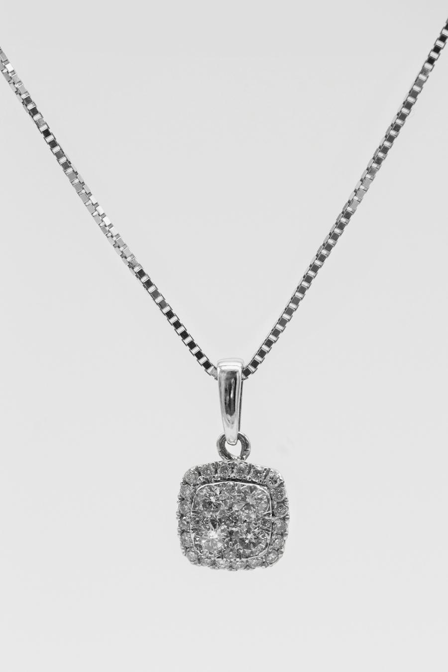 Un collar de plata con un colgante cuadrado de cristales sobre un fondo gris claro