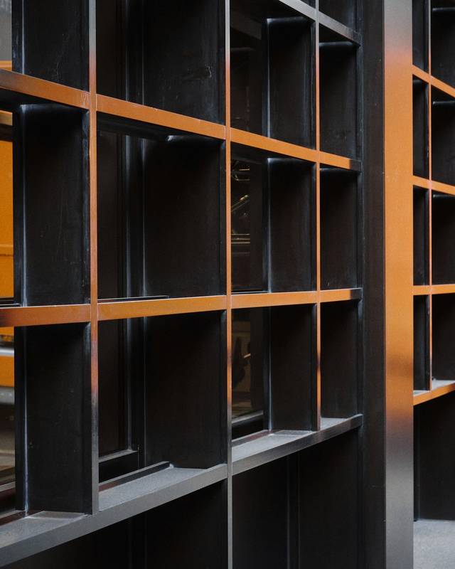Estantería de acero negro con nichos y tablas de madera encendidas por la luz