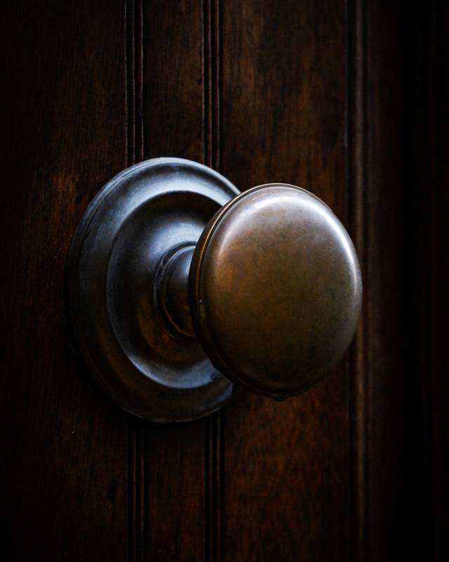 Pomo de bronce envejecido sobre una puerta de madera oscura