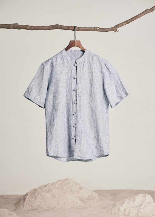 Camisa de lino a rayas finas azules colgada de una rama