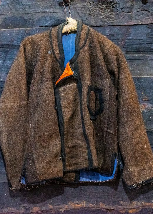 Chaqueta corta de fieltro café colgada de una pared de madera oscura