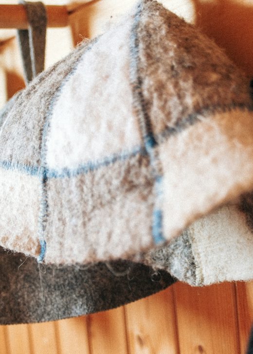 Gorros de fieltro de lana en tonos tierra colgados de una pared de madera