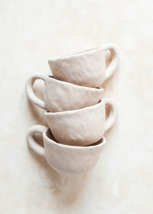 Cuatro tazas de cerámica rosa pálido apiladas sobre un fondo claro