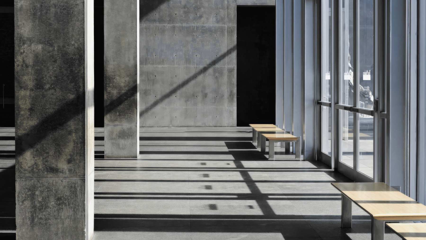 Corredor de hormigón con luz de sol y bancas de madera