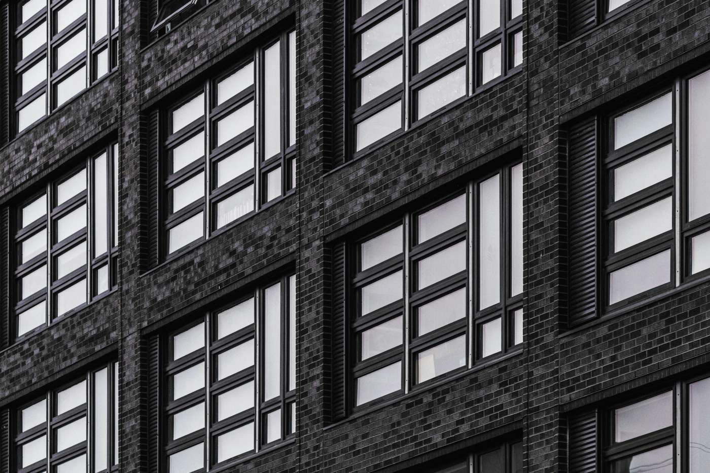 Fachada de ladrillo oscuro con ventanas de marco negro