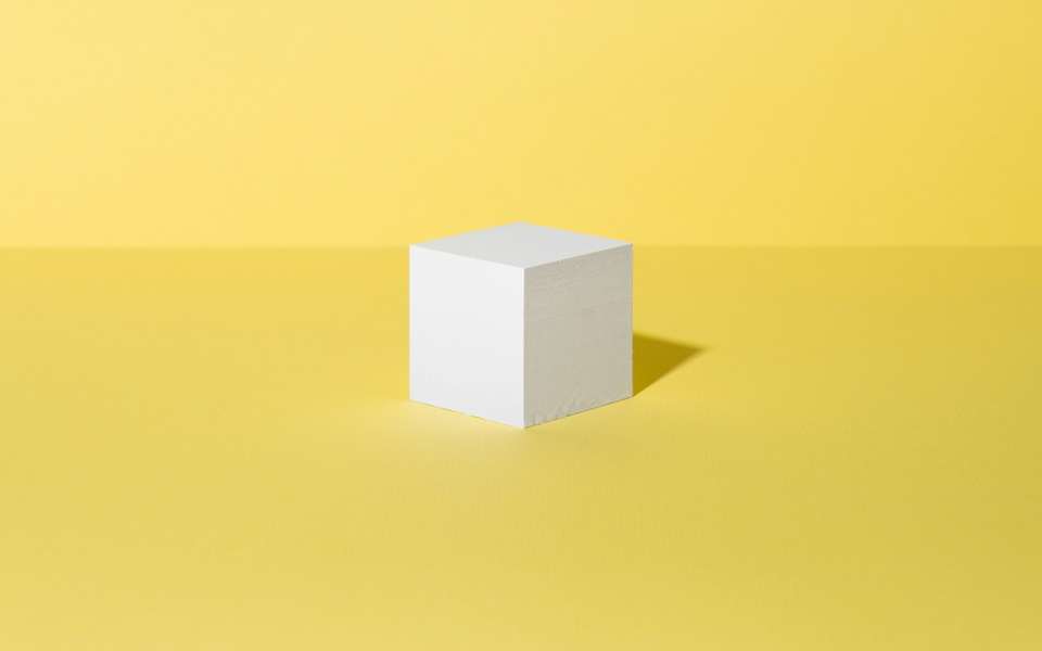 Un cubo blanco sobre un fondo amarillo liso
