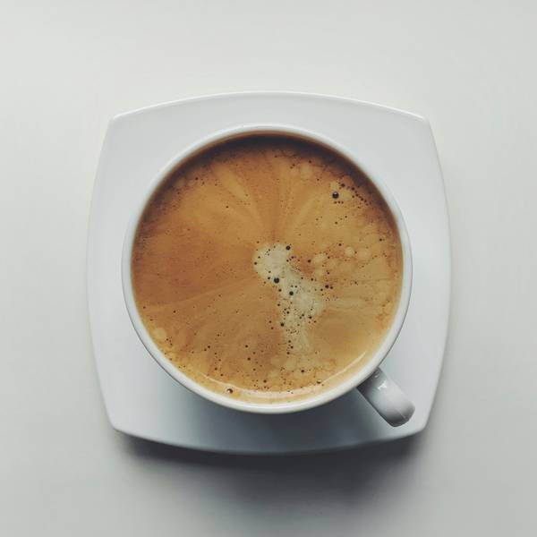 Taza de café con espuma sobre un plato cuadrado, vista desde arriba