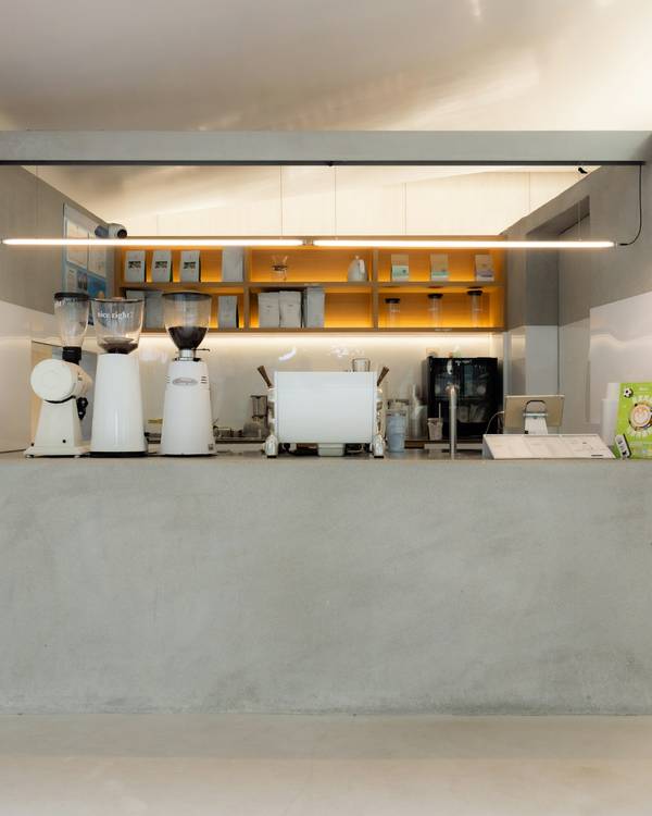 Mostrador de hormigón de un café, con máquinas y estantes al fondo