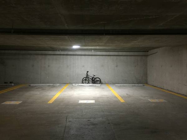 Una bicicleta solitaria en una plaza de estacionamiento vacía, entre líneas amarillas