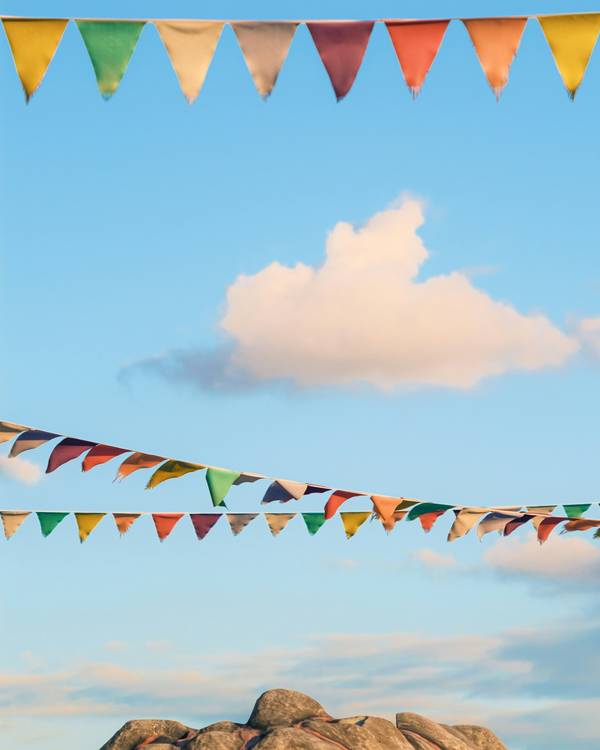 Banderines de colores y una nube sobre un cielo celeste