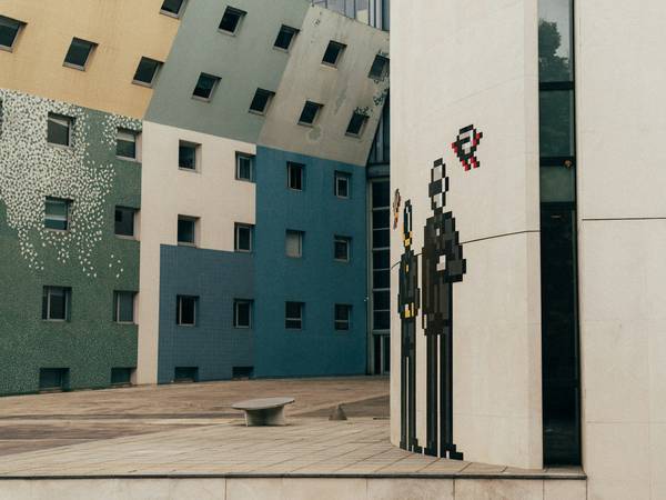 Edificio de fachadas de colores con una figura de pixeles pintada en el muro