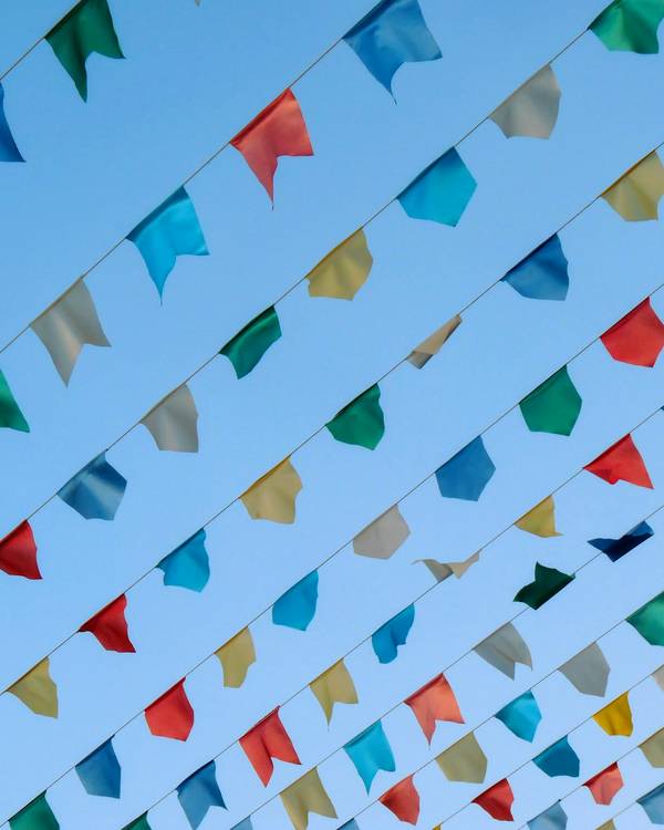 Hileras de banderines de colores que cruzan un cielo azul en diagonal