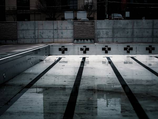Piscina vacía con calles oscuras y charcos en el fondo