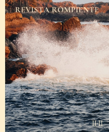 Una ola que revienta contra rocas rojizas y levanta una nube de espuma