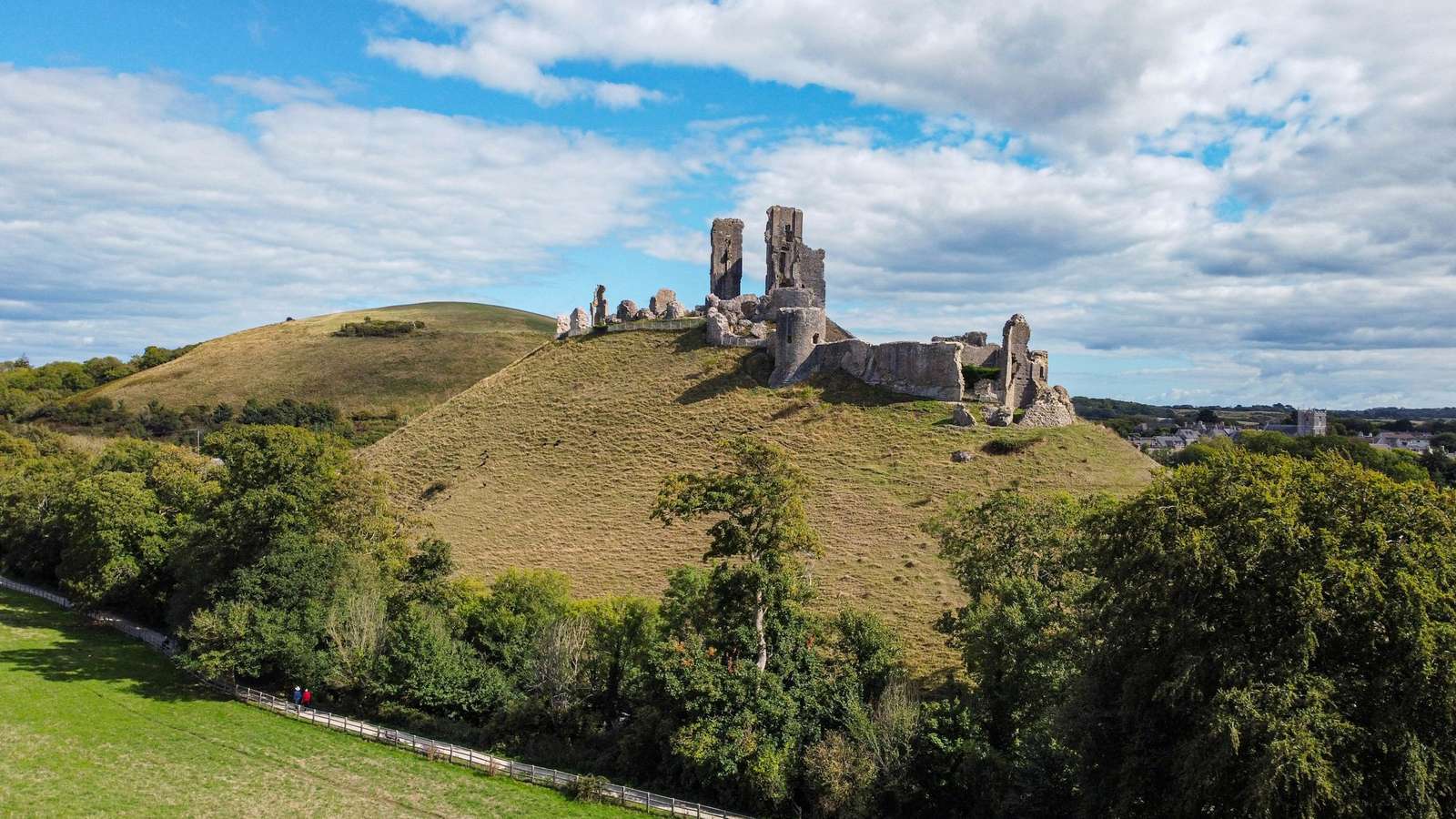 Ruinas de piedra sobre una colina de hierba bajo un cielo con nubes