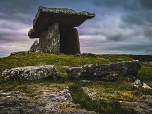 Gran losa de piedra apoyada sobre otras dos bajo un cielo de tormenta