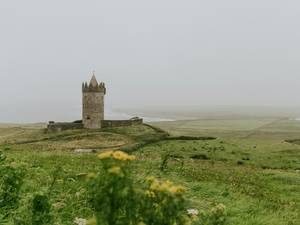 Torre de piedra en la niebla sobre un campo verde