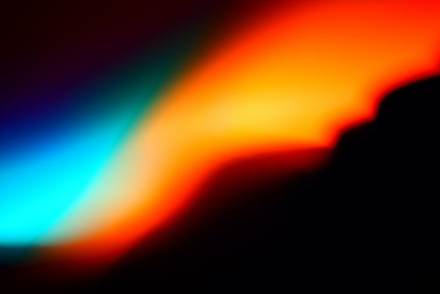 Mancha de luz azul, naranja y verde sobre un fondo negro