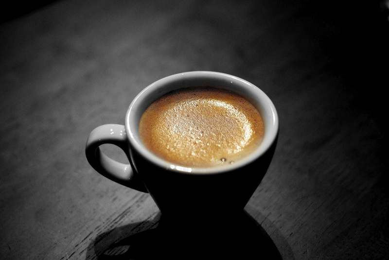 Taza de café con espuma sobre fondo oscuro