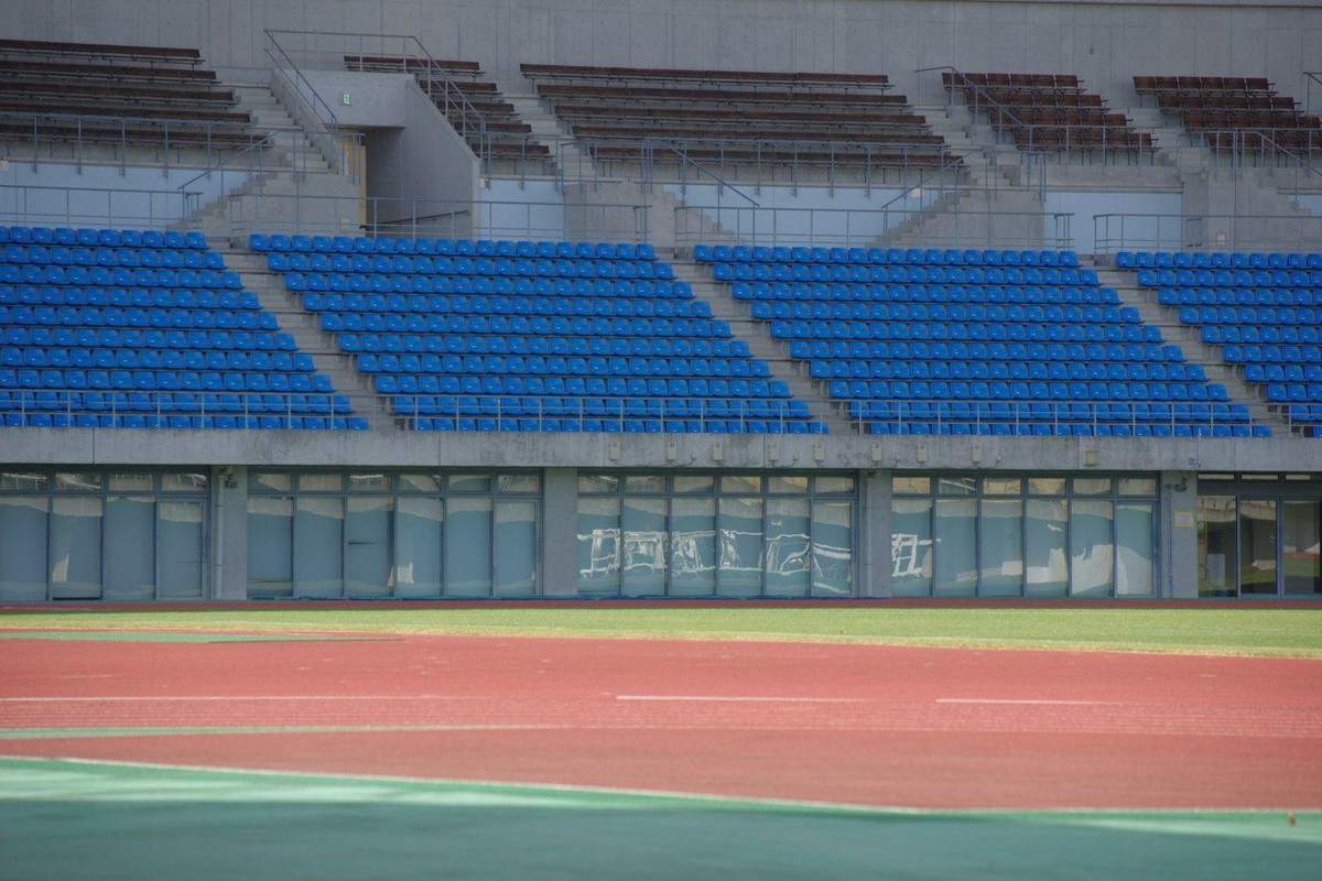 Gradas azules vacías frente a una pista roja