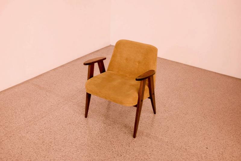 Butaca color miel con brazos de madera en un cuarto de piso claro