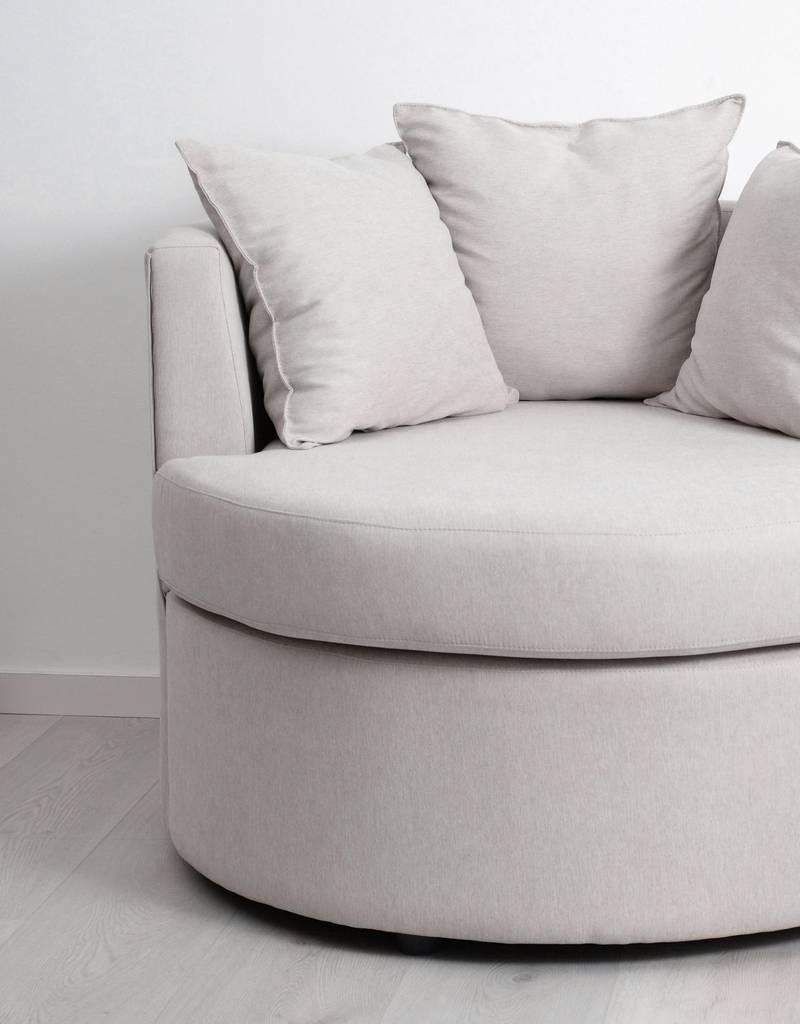 Sillón blanco redondeado con cojines sobre un fondo blanco