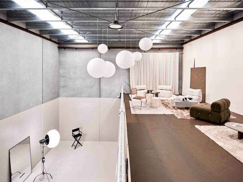 Galería abierta con sillones, lámparas esféricas y una luz amplia
