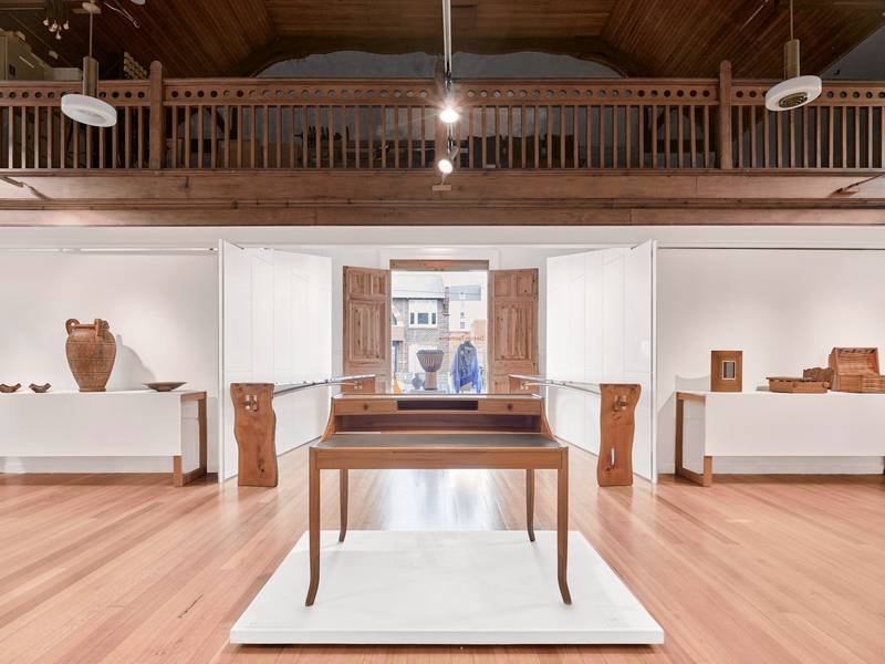 Sala de exposición con una mesa de madera sobre una tarima blanca
