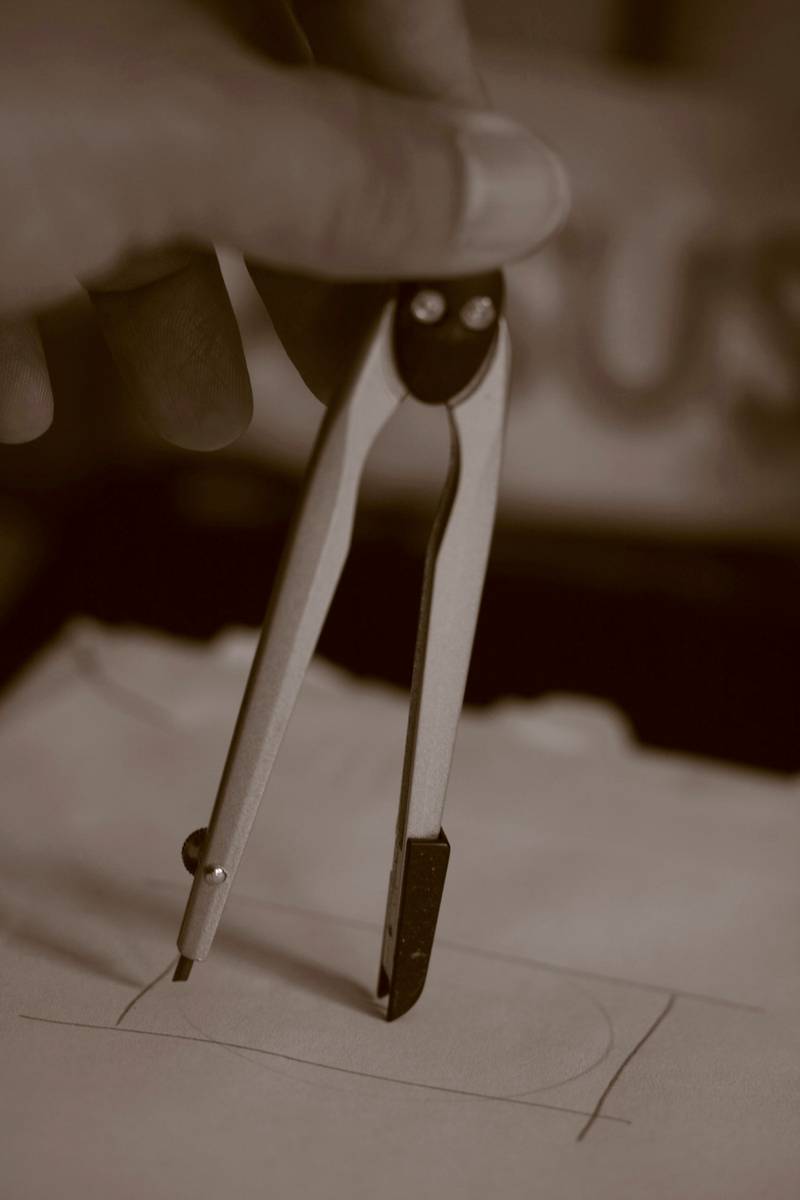 Compás de metal apoyado sobre papel, en tonos sepia