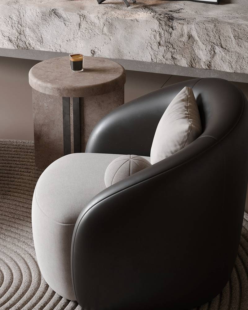 Sillón curvo de cuero oscuro junto a una mesa de piedra