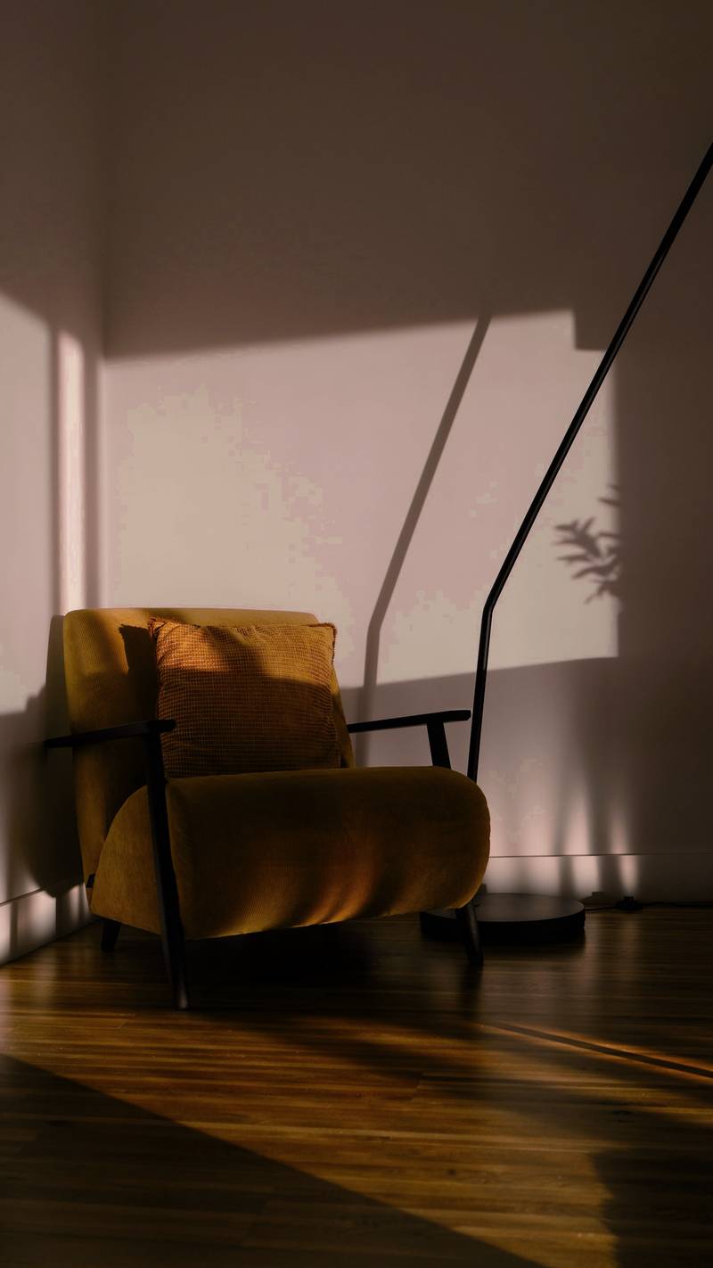 Sillón color miel en un rincón con sombras largas de la tarde