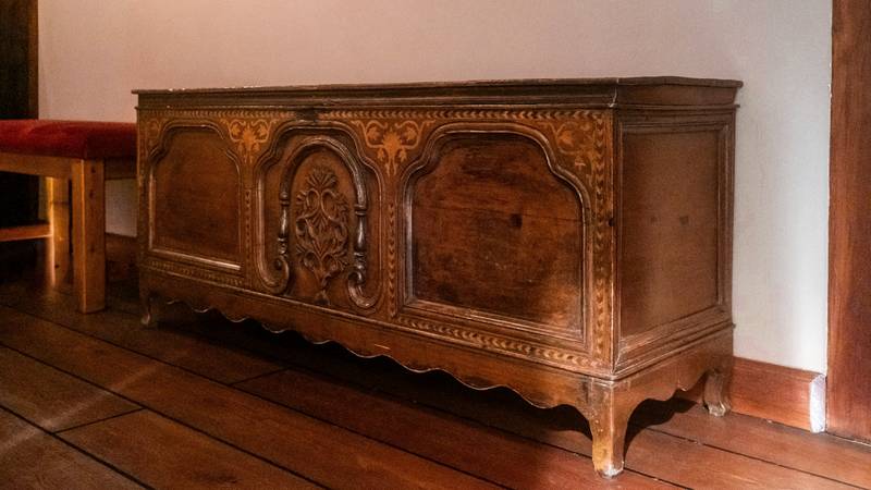 Cofre antiguo de madera tallada sobre un piso de tablones