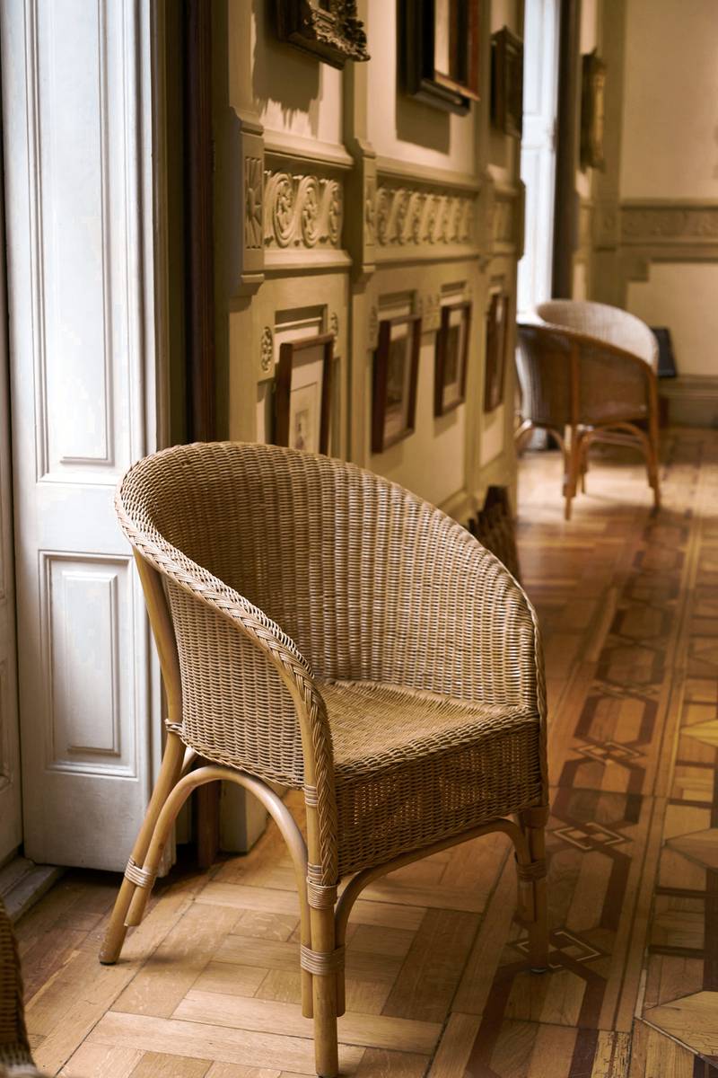 Sillón de mimbre en una sala antigua con luz de ventana