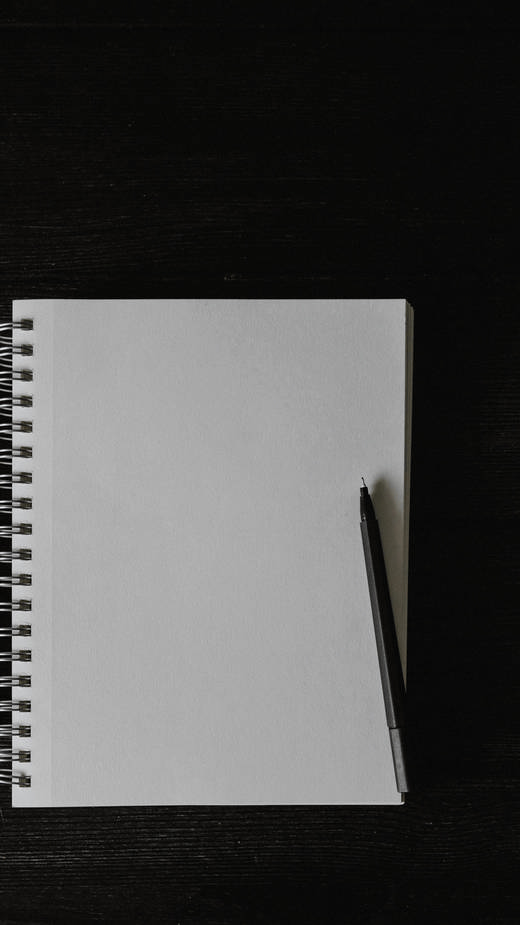 Cuaderno de espiral de hojas blancas con un lápiz, sobre una mesa negra