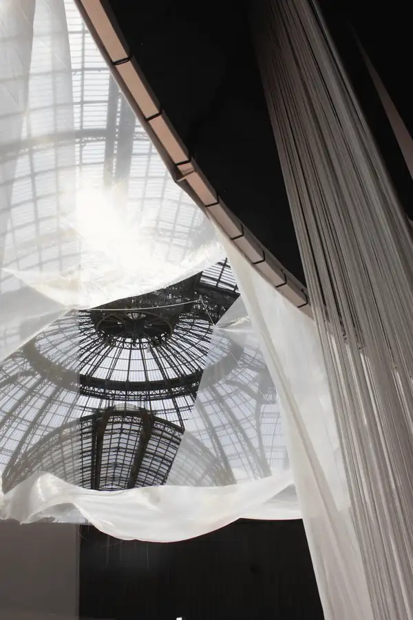 Telas blancas bajo una cúpula de vidrio, con el sol al fondo
