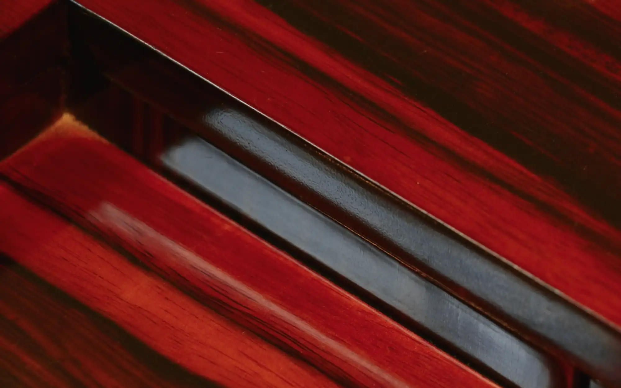 Madera lacada en rojo con una tira de metal oscuro en diagonal