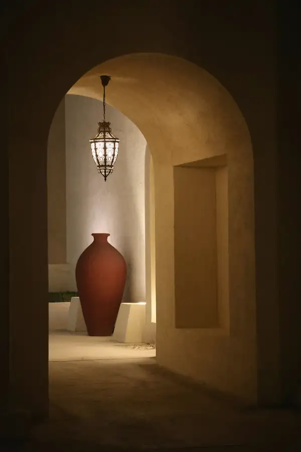 Vasija roja en un arco iluminado por una lámpara colgante