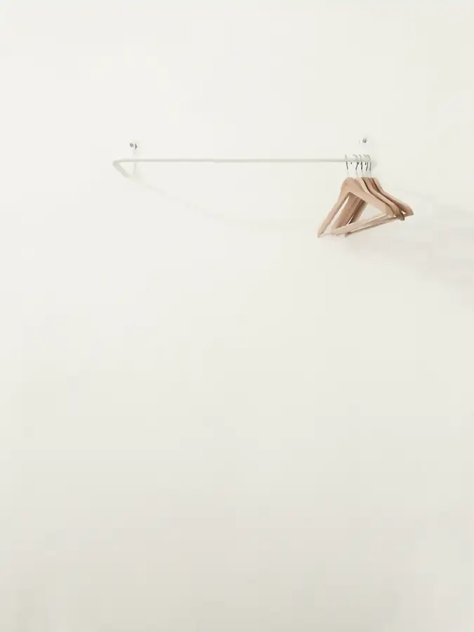 Una barra blanca con unas perchas de madera