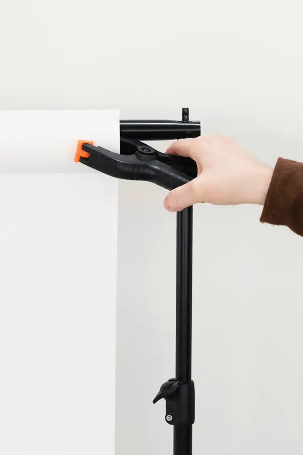 Una mano sujeta el papel de fondo con una pinza