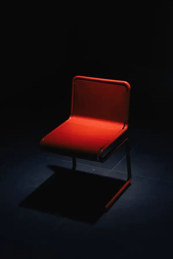 Una silla roja sola en una sala oscura