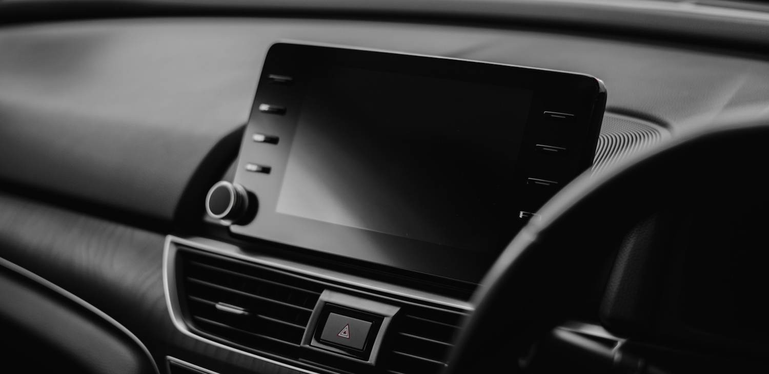 Detalle del tablero de un auto oscuro con una pantalla táctil y las salidas de aire