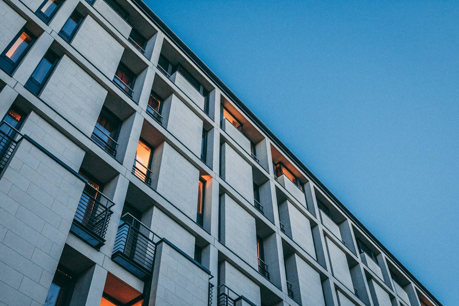 Fachada de hormigón con ventanas encendidas al atardecer
