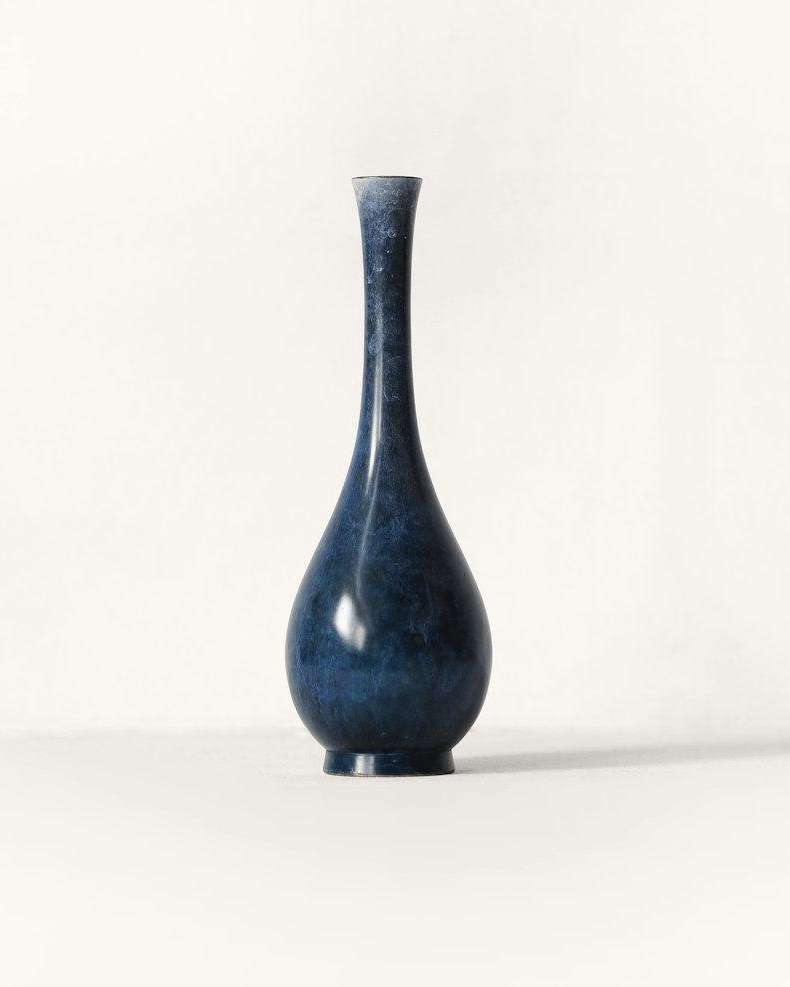 Jarrón esbelto azul oscuro sobre un fondo claro
