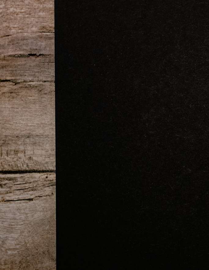 Borde de un cuaderno de tapa negra sobre tablones de madera gastada