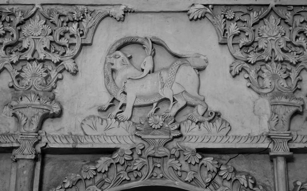 Relieve en piedra clara con un animal entre volutas