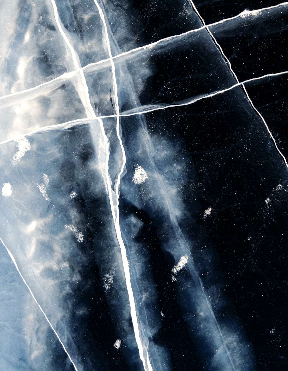 Hielo oscuro con fisuras blancas que se cruzan